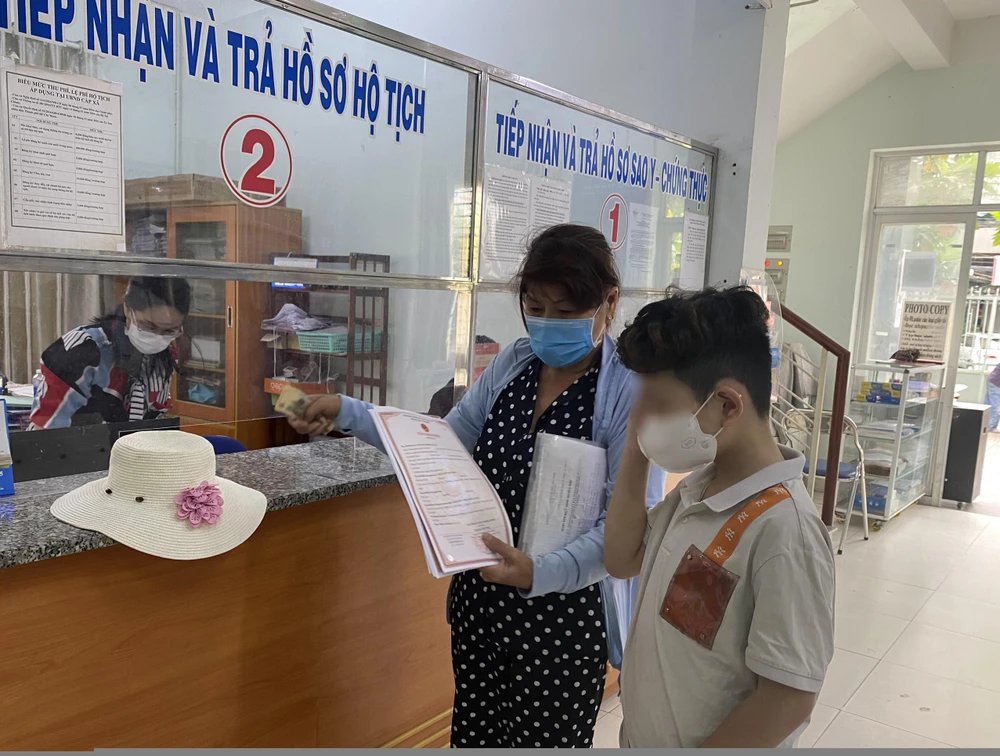 Tuấn cùng mẹ lên UBND phường 12, quận Bình Thạnh nhận giấy khai sinh sáng 25-11-2021. Ảnh: HỮU ĐĂNG