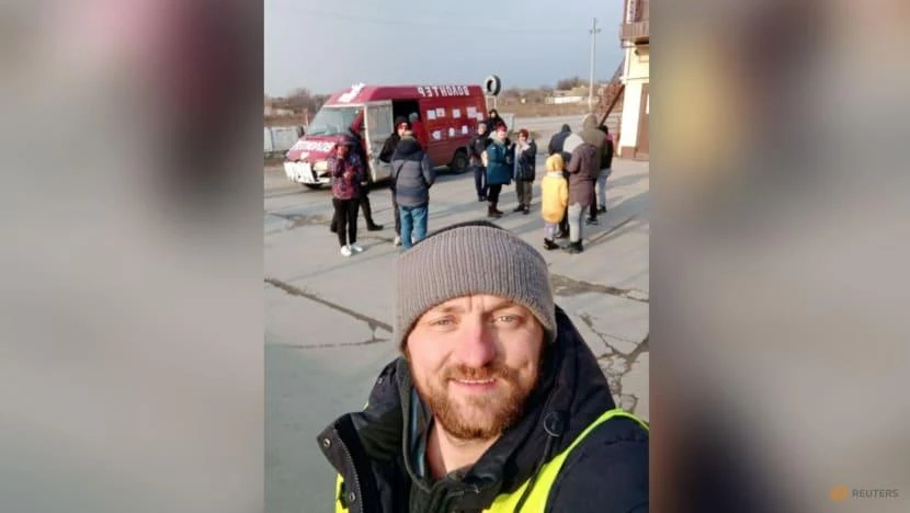 Mykhailo Puryshev chụp một bức ảnh phía trước chiếc xe anh sử dụng để sơ tán những người dân khỏi TP Mariupol. Ảnh: REUTERS