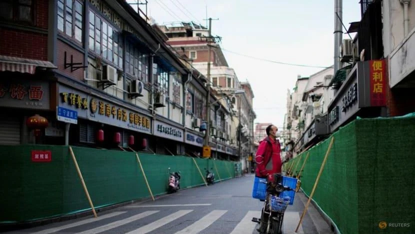 Một nhân viên giao hàng đứng trước một khu dân cư đang bị phong tỏa ở Thượng Hải, Trung Quốc, ngày 9-5. Ảnh: REUTERS