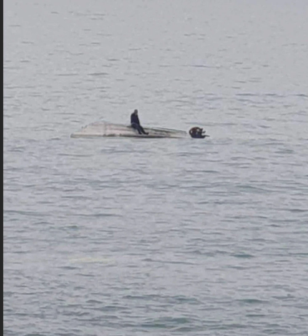 Một nạn nhân sống sót sau vụ lật thuyền ngồi đợi giải cứu trên mũi con thuyền. Ảnh: TWITTER