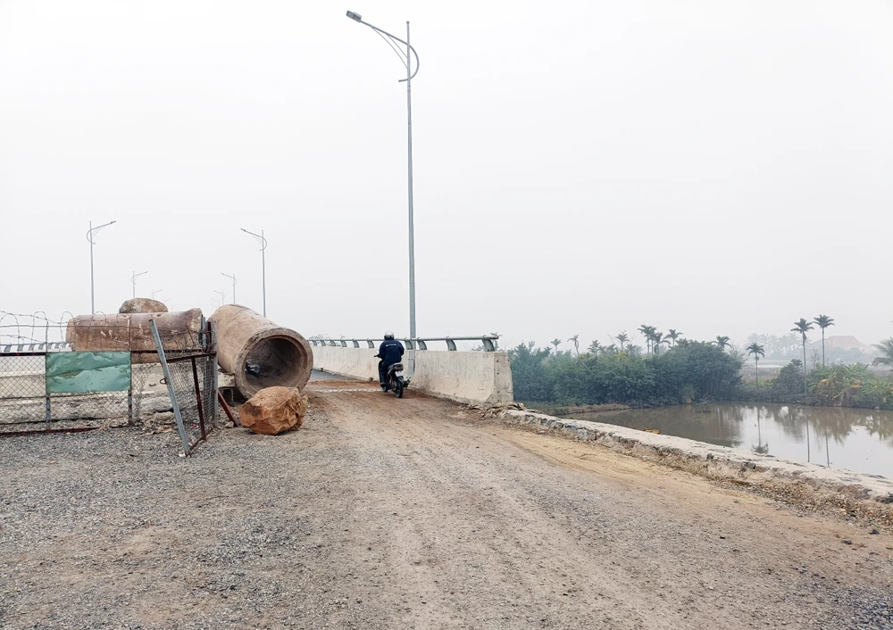 Người dân tháo rào để đi qua cầu Văn Úc - thuộc dự án tuyến đường bộ ven biển Hải Phòng – Thái Bình. Ảnh: NGỌC SƠN
