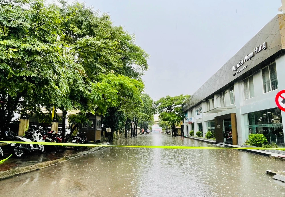 Tuyến đường dẫn từ phố Phạm Hùng vào Bệnh viện 198 ngập sâu, đơn vị cấp thoát nước đã phải giăng dây cảnh báo. Ảnh: NHƯ LOAN
