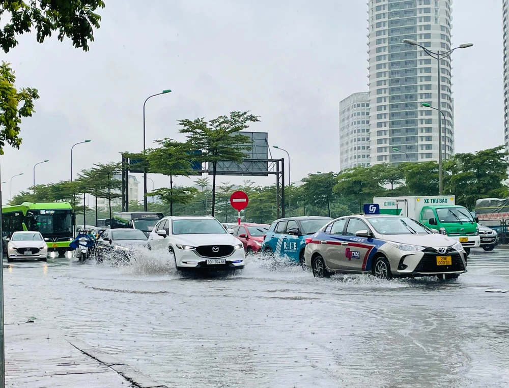 Mặt đường Phạm Hùng dù vẫn còn tình trạng ngập, tuy nhiên lượng nước không quá nhiều, các phương tiện di chuyển không gặp quá nhiều khó khăn. Ảnh: NHƯ LOAN