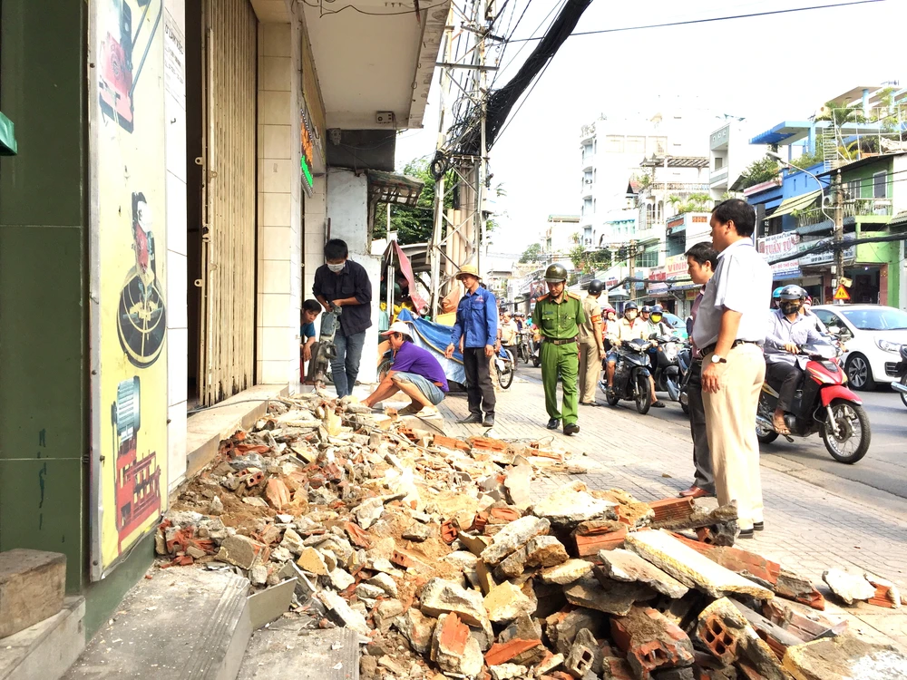 Việc tháo dỡ, làm sạch vỉa hè thu hút sự quan tâm của người dân, người đi đường. Ảnh: Quỳnh Như