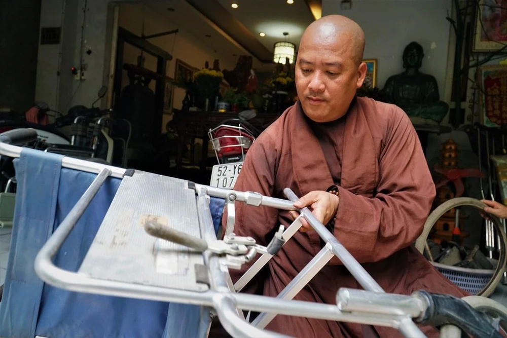 Sư thầy Đức Minh đang sửa chửa một chiếc xe lăn cũ.