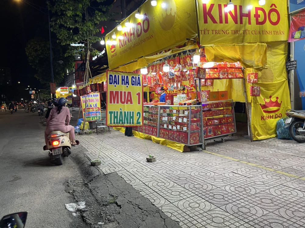 Một điểm trên đường Trường Chinh (quận 12) bán treo biển "Đại hạ giá mua 1 thành 2" để thu hút người tiêu dùng. Ảnh: THU HÀ