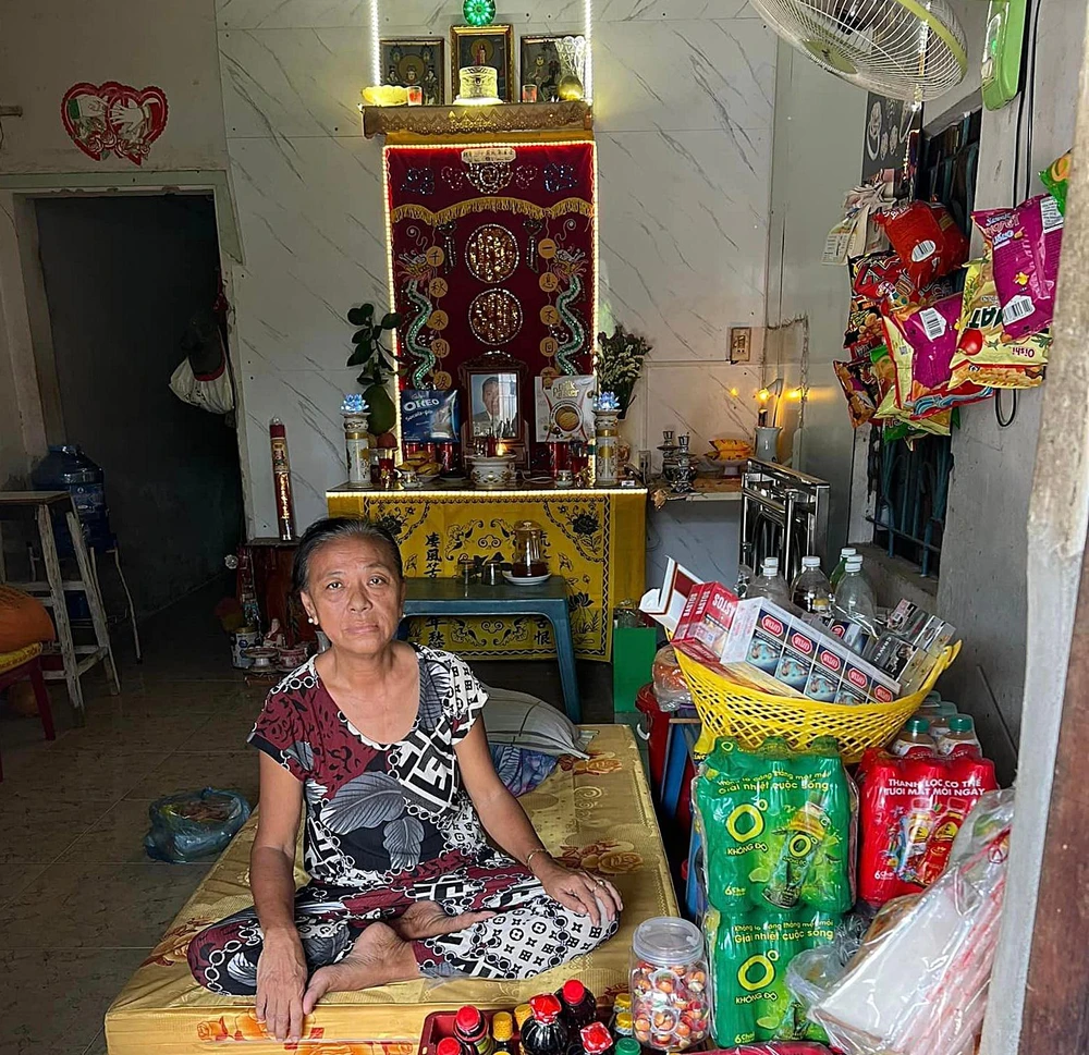 Vợ ông Hạ trong căn nhà trọ phía sau là bàn thờ chồng. Ảnh: HQH