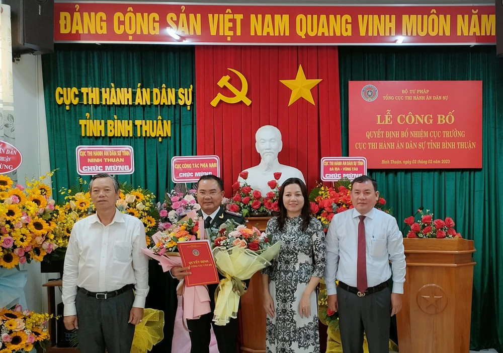 Bà Trần Thị Phương Hoa trao quyết định và cùng các đại biểu tặng hoa chúc mừng ông Huỳnh Văn Hùng. Ảnh ĐT.