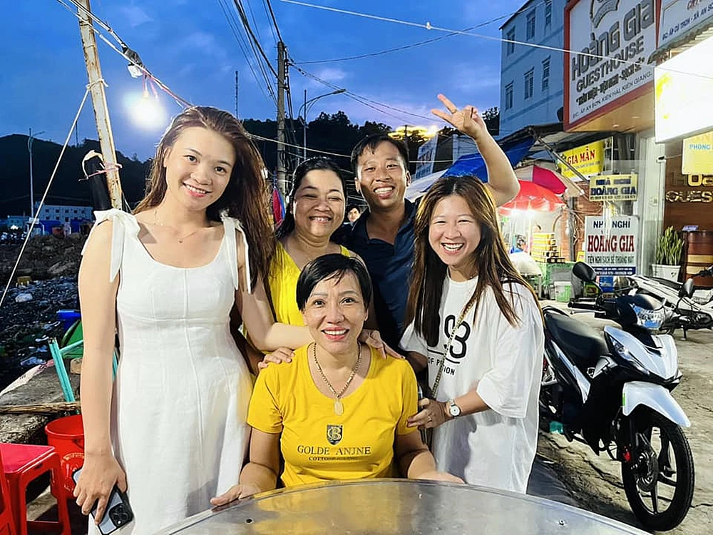 Du khách đến từ TPHCM chúc mừng người phụ nữ áo vàng (ngồi) trúng 2 tờ vé số độc đắc. Ảnh: Đào Trang