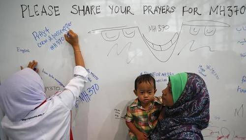 Một phụ nữ viết những lời cầu nguyện cho các nạn nhân bị mất tích. Ảnh: Reuters