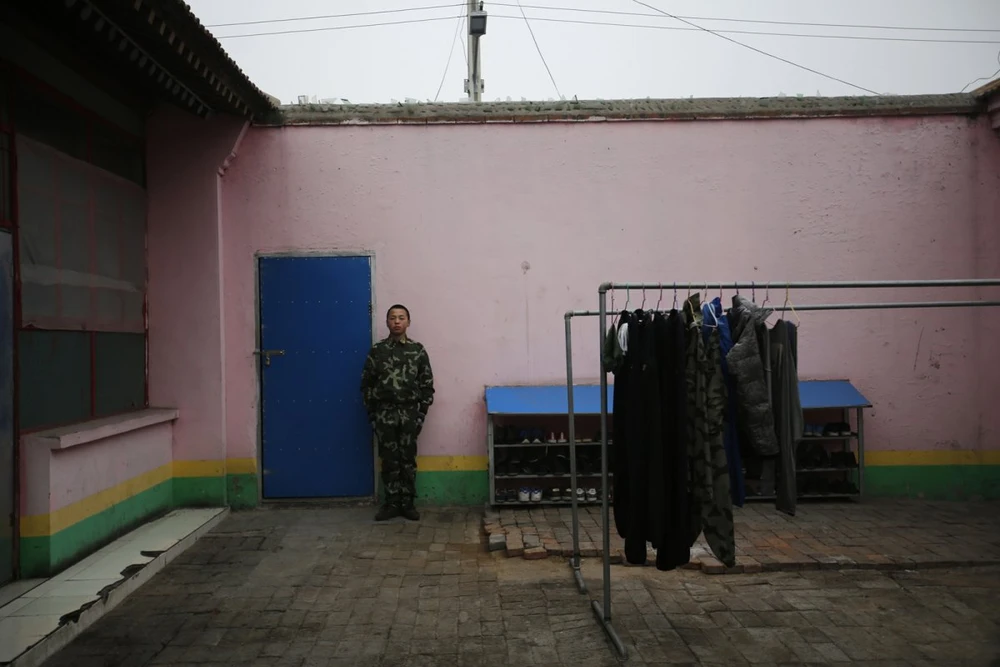 Một học viên đứng ngoài cửa vào ký túc xá ở Qide.