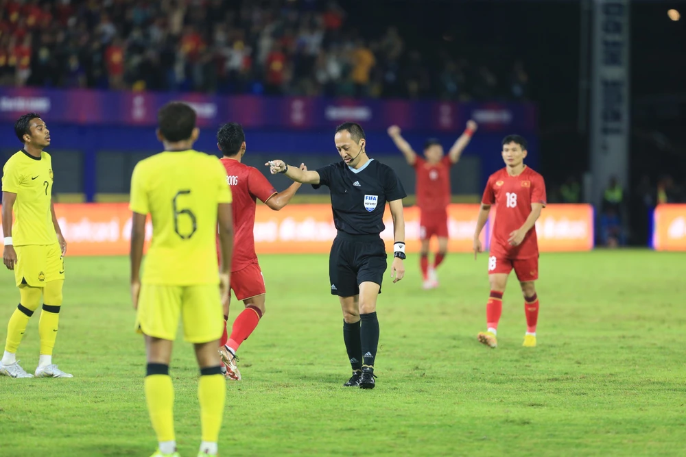 Trọng tài chỉ tay vào chấm 11m bất chấp sự phản đối của cầu thủ Malaysia.
