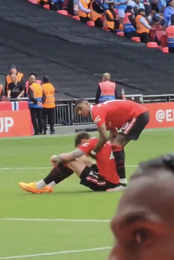 Marcus Rashford đỡ Wout Weghorst đứng dậy. ẢNH: SUN SPORTS