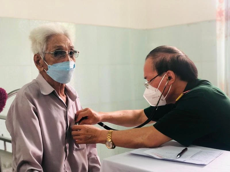 Bác sĩ Trần Văn Thành, Trưởng Ban công tác xã hội - Bệnh viện Quân y 175 tận tình khám bệnh cho người cao tuổi. Ảnh: PHONG ĐIỀN