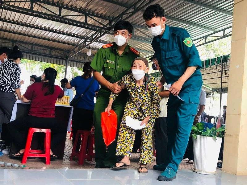 Lực lượng dân phòng, công an trên địa bàn hỗ trợ người cao tuổi đến khám bệnh. Ảnh: PHONG ĐIỀN
