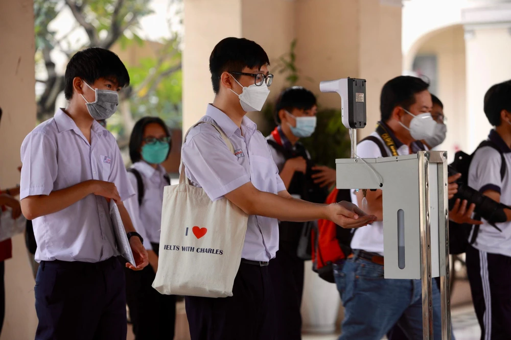 Thí sinh rửa tay, đo nhiệt độ trước khi vào phòng thi. Ảnh: NGUYỆT NHI