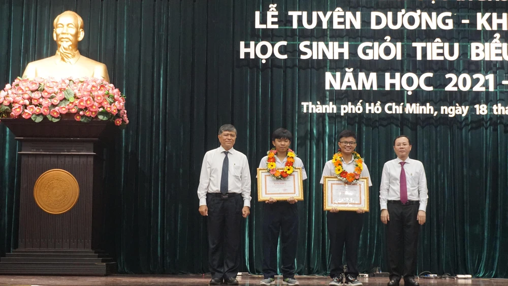 Ông Nguyễn Văn Hiếu, Phó Bí thư Thành uỷ TP.HCM (bìa phải) và ông Nguyễn Văn Hiếu, Giám đốc Sở GD&amp;ĐT TP.HCM (bìa trái) trao tặng bằng khen cho hai học sinh đạt giải Olympic quốc tế. Ảnh: NQ