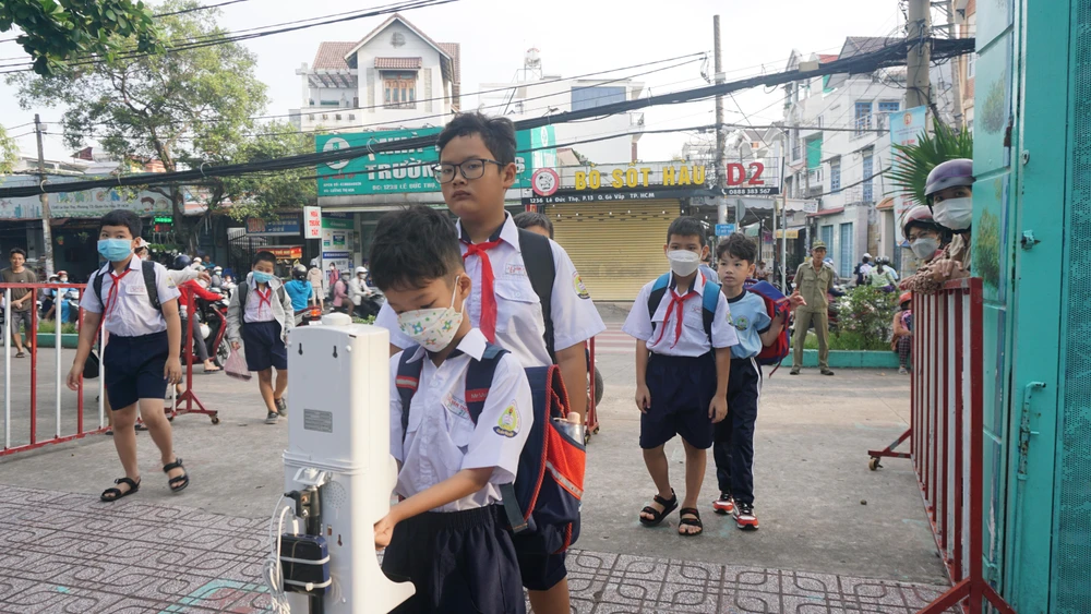 Nhà trường luôn quan tâm đến các biện pháp phòng dịch. Vì thế, trước khi vào trường, các em đều phải đo thân nhiệt và rửa tay sát khuẩn. Ảnh: NGUYỄN QUYÊN