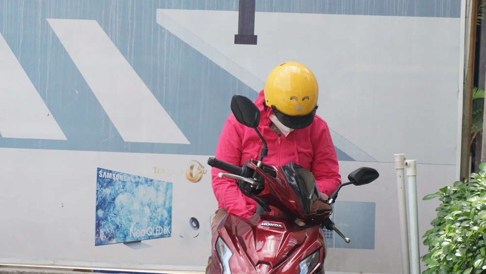 Phụ huynh ngồi đợi con trước cổng trường mặc cho nắng nóng. Ảnh: NGUYỄN QUYÊN