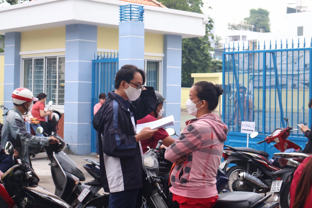 Từ sáng, phụ huynh đã chở con đến điểm thi và không quên dặn dò con khi làm bài phải thật bình tĩnh. Ảnh: TRẦN MINH