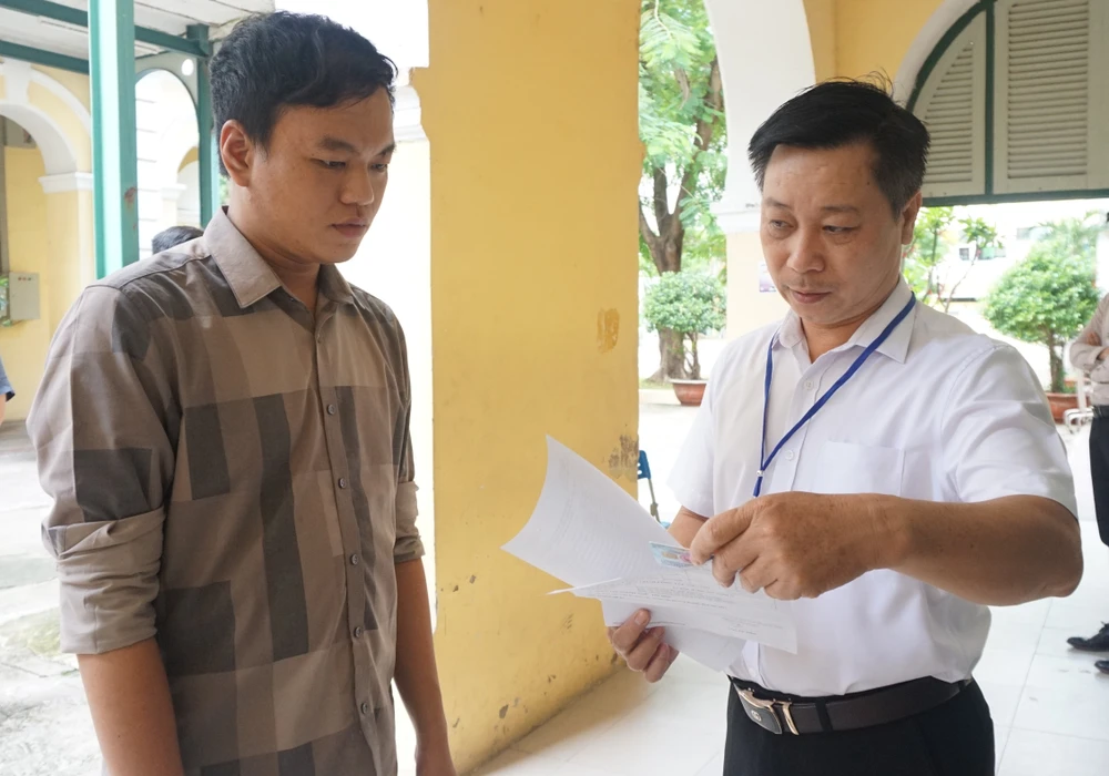 Giám thị kiểm tra giấy tờ của thí sinh trước khi vào phòng thi. Ảnh: NGUYỄN QUYÊN