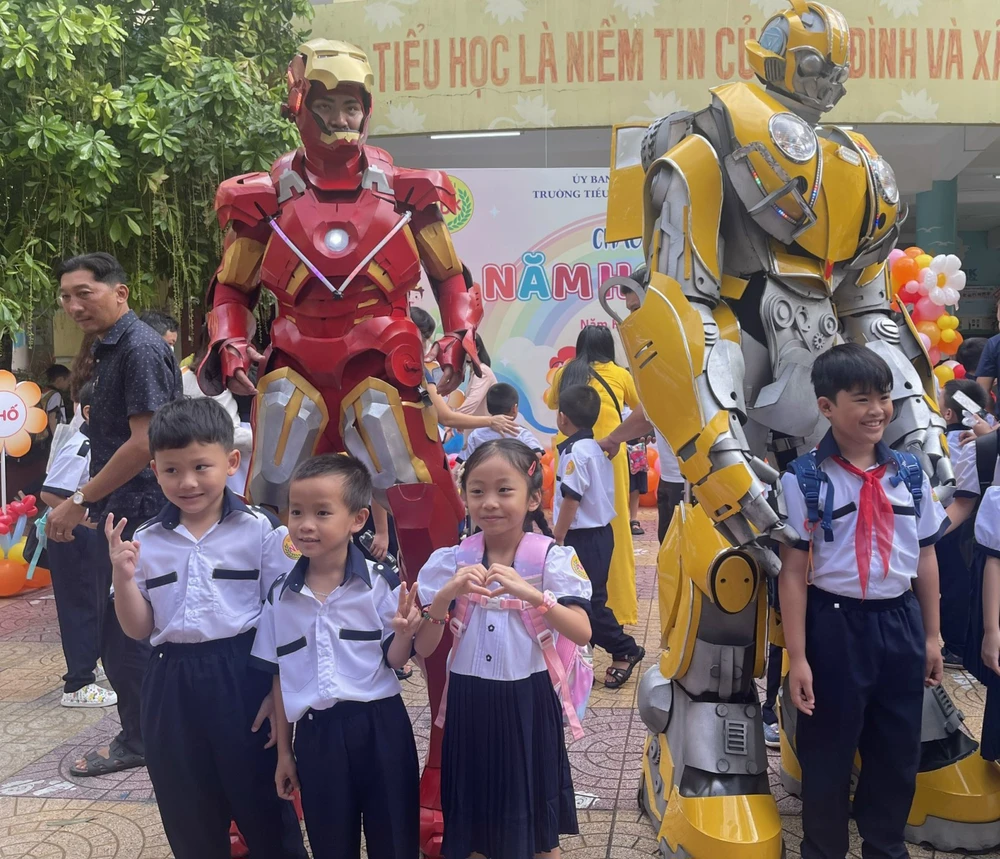 Học sinh chụp hình với hai nhân vật robot. Ảnh: PHAN NGA