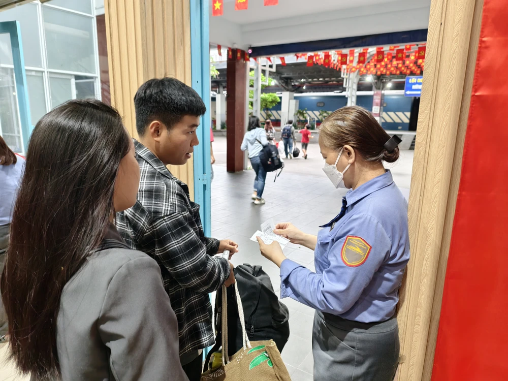Nhân viên đường sắt kiểm tra vé và giấy tờ tuỳ thân của hành khách trước khi vào cửa. Ảnh: TN