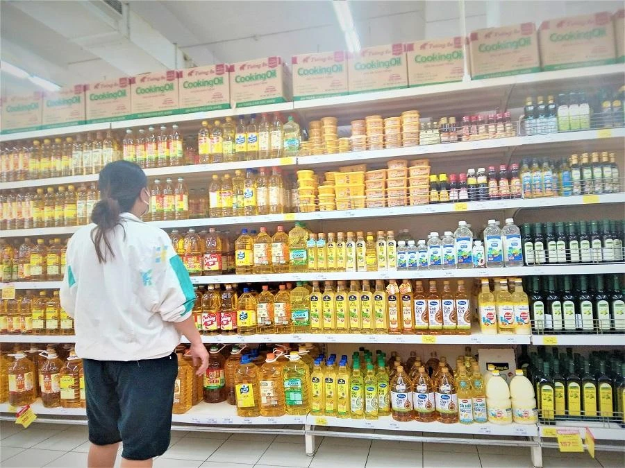 Người tiêu dùng phân vân chọn các loại dầu ăn trên kệ siêu thị. ẢNH: TÚ UYÊN