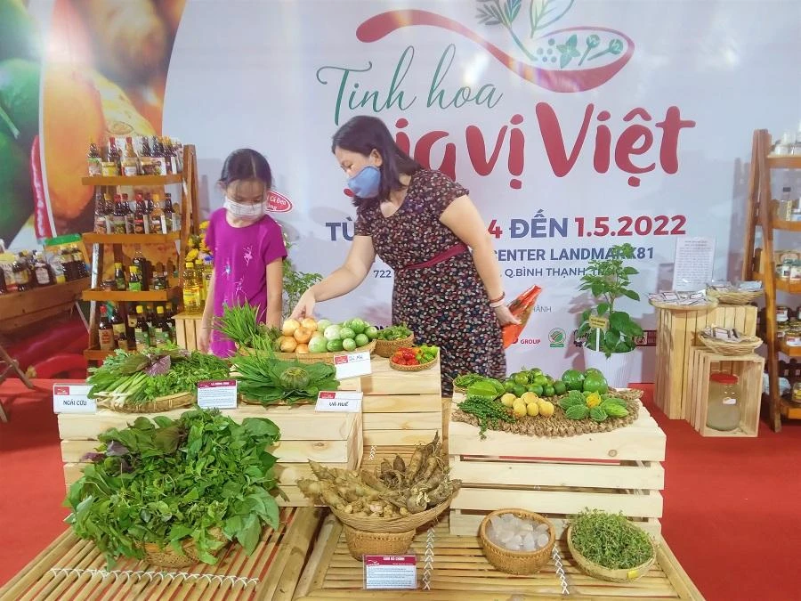 Vị khách tham quan này đang hướng dẫn cho con gái thông tin về các loại rau gia vị trưng bày tại lễ hội. ẢNH: TÚ UYÊN