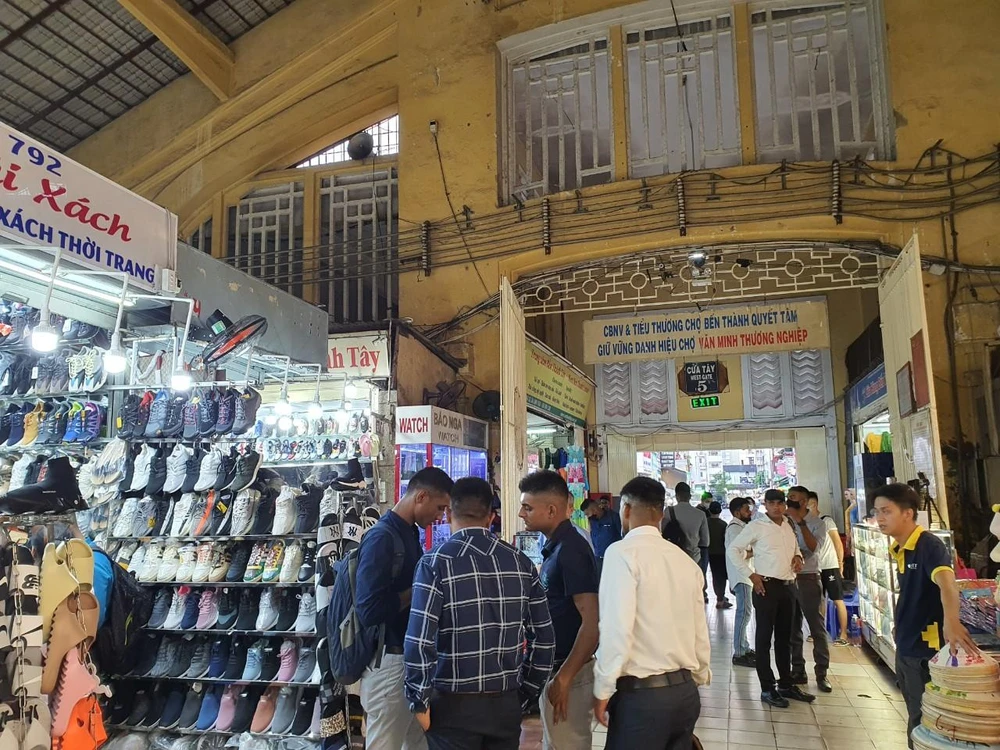 Du khách nam ghé tham quan hàng hóa tại sạp túi xách thời trang