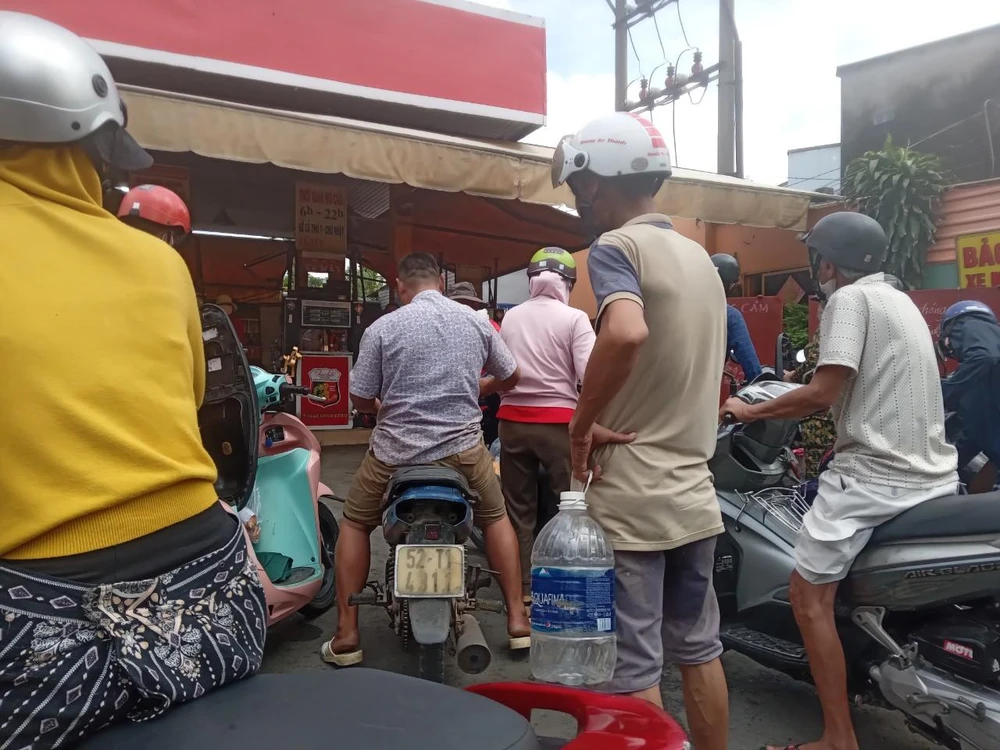 Một người dân đem theo bình nước suối 5 lít đến cửa hàng xăng quận Bình Tân.