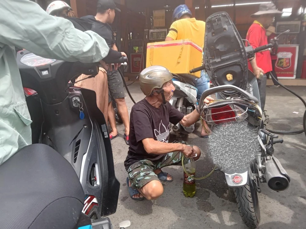 Một người dân tự hút xăng từ xe ra chai nước ngọt