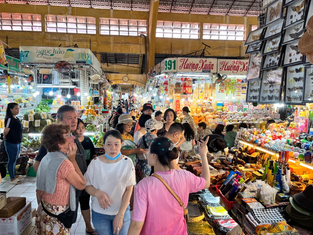 Một sạp bán đồ lưu niệm có nhiều khách đến hỏi mua sắm