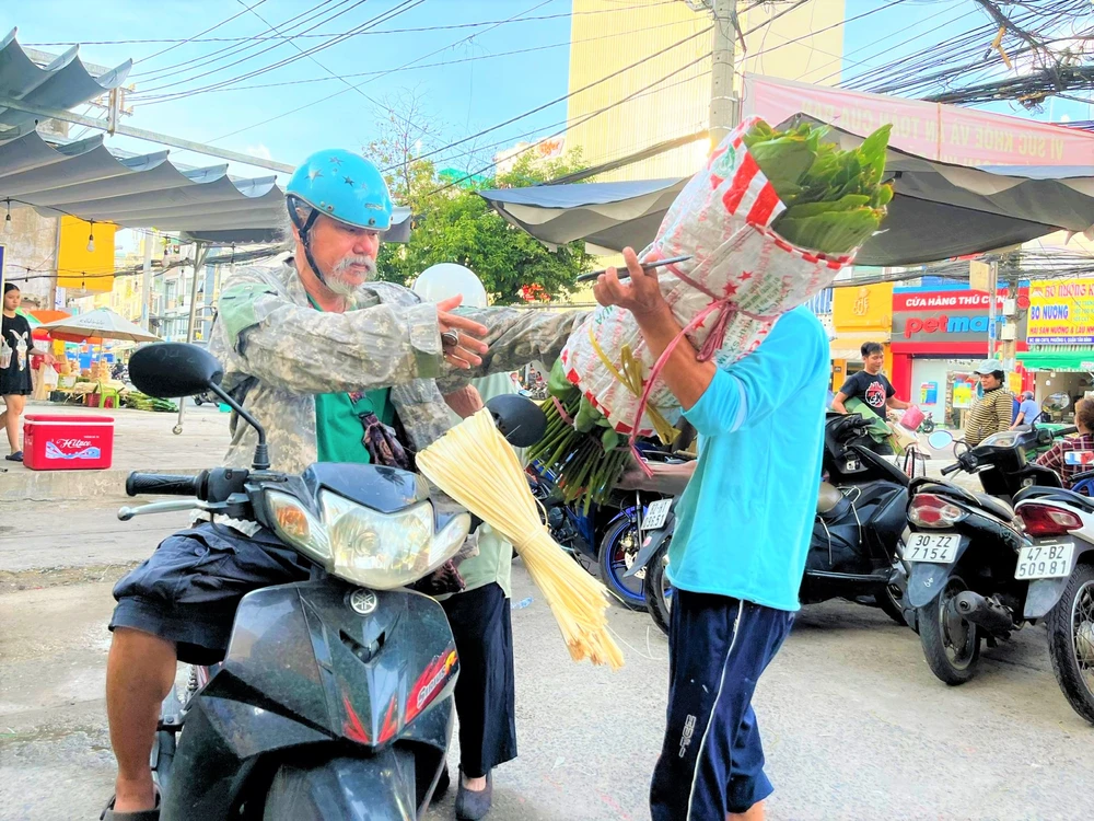Ngày 23 tháng Chạp, một người dân đưa người thân mua lá dong, lạt về nấu bánh chưng