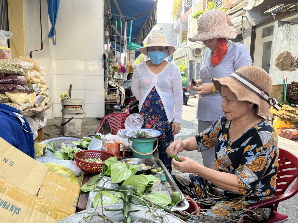 Khách đặt nhiều nên một khách quen bổ cau dùm cho người bán đang têm trầu.