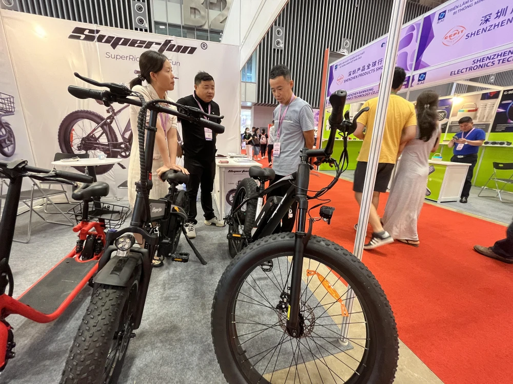 Xe đạp điện giá 600 USD chiếc (ngoài cùng bên phải) đang được khách tham quan tìm hiểu