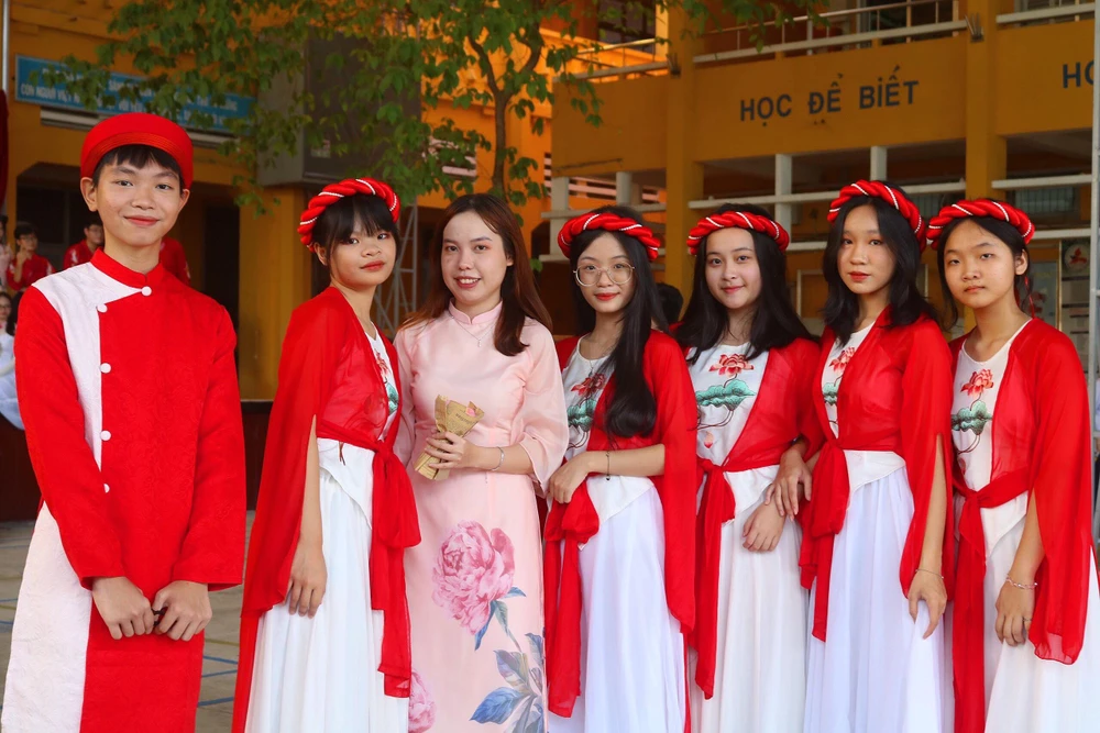 Em Phan Ngọc Vân (ở giữa) thích thú chụp ảnh lưu niệm cùng giáo viên dạy Văn và các bạn sau buổi biểu diễn. Ảnh: TÚ NGÂN