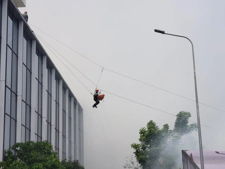 Cảnh sát đu dây đưa nạn nhân từ tầng thượng xuống đất an toàn. Ảnh: TS