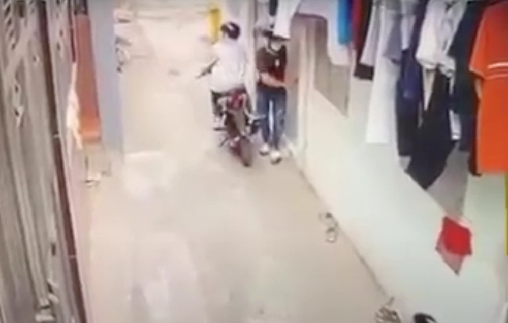 An ngồi trên xe máy, Hiền đang phá khoá phòng trọ để trộm cắp được camera ghi lại. Ảnh: Cắt từ clip