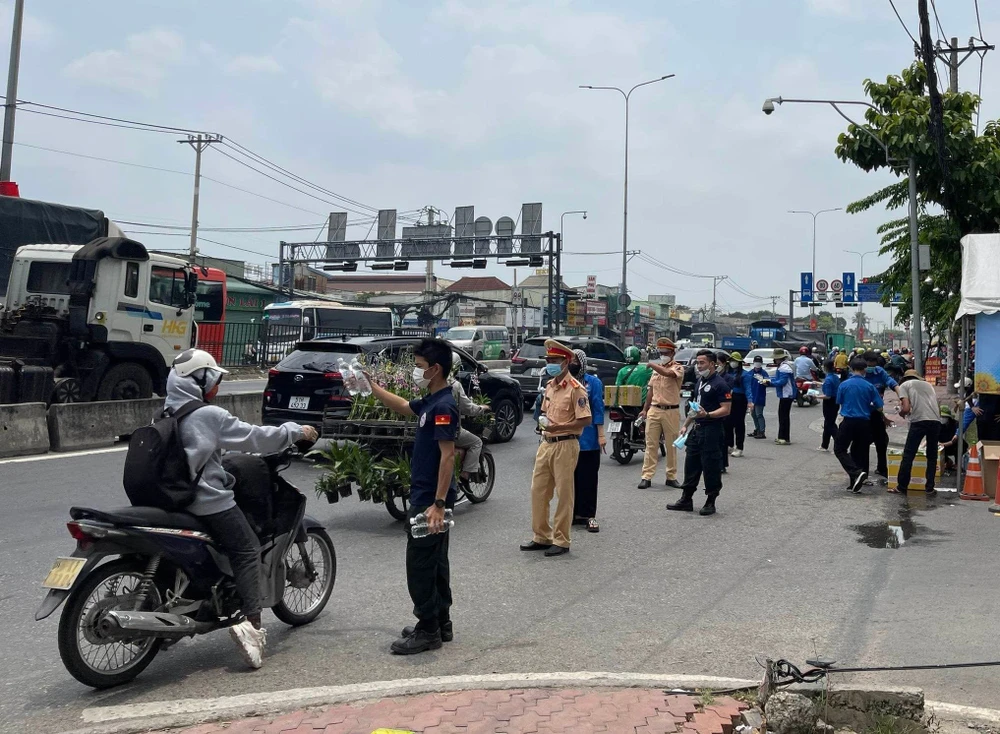 Lực lượng CSGT và tình nguyện viên tham gia phát nước, nón bảo hiểm miễn phí cho người dân về quê đón lễ. Ảnh: TS