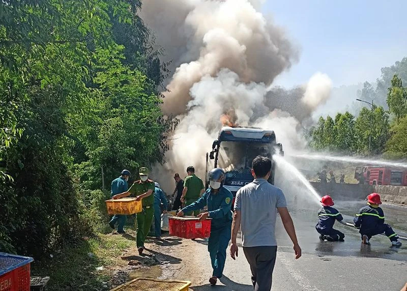 Lực lượng chức năng, người dân giúp đưa hàng hóa ra khỏi chiếc xe bị cháy. Ảnh: V.PHONG