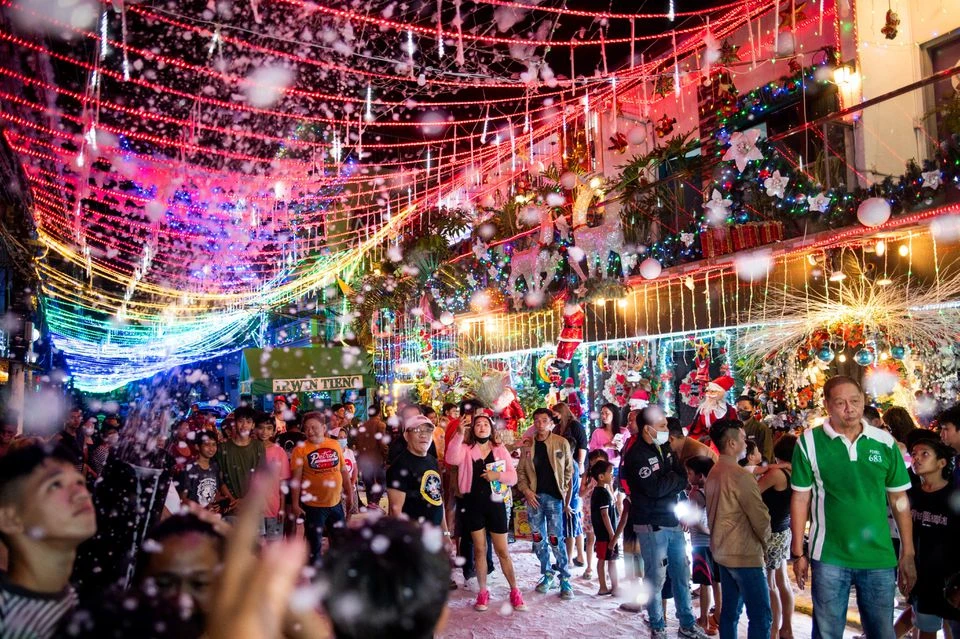 Mọi người thích thú với tuyết giả bên ngoài một ngôi nhà theo chủ đề Giáng sinh ở thủ đô Manila (Philippines) ngày 11-12. Ảnh: REUTERS