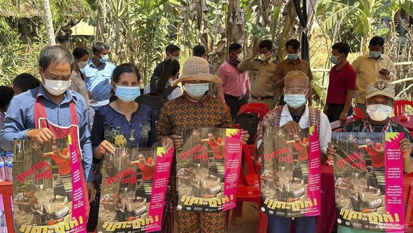 Người dân Campuchia cầm áp phích tuyên truyền về mối đe dọa của cúm gia cầm H5N1 ở tỉnh Prey Veng ( Campuchia) ngày 23-2. Ảnh: AP