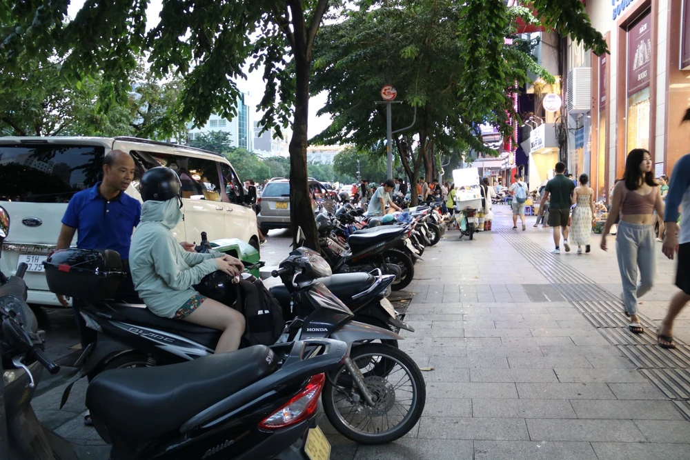 Xe máy đậu kín vỉa hè đường Nguyễn Huệ.