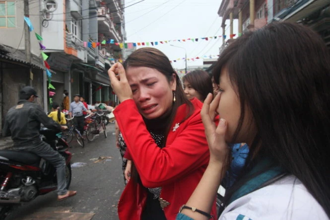 Chị Trần Thị Loan (áo đỏ) khóc nghẹn khi toàn bộ số hàng trị giá cả trăm triệu đồng bị thiêu rụi - Ảnh: Tiến Thắng