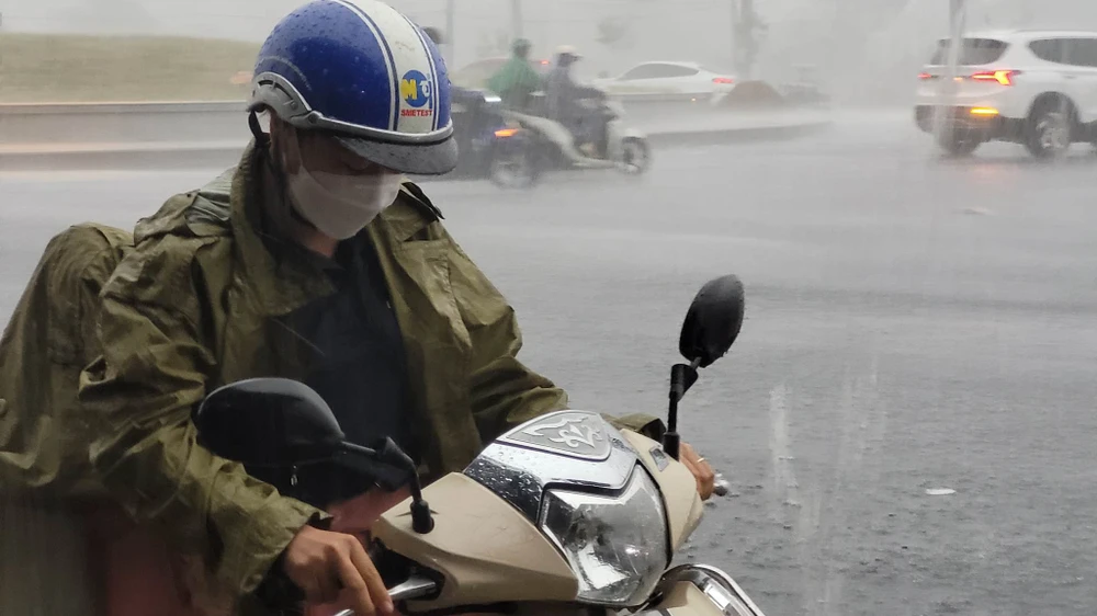 Một người dân vội vã tấp vào lề để mặc áo mưa