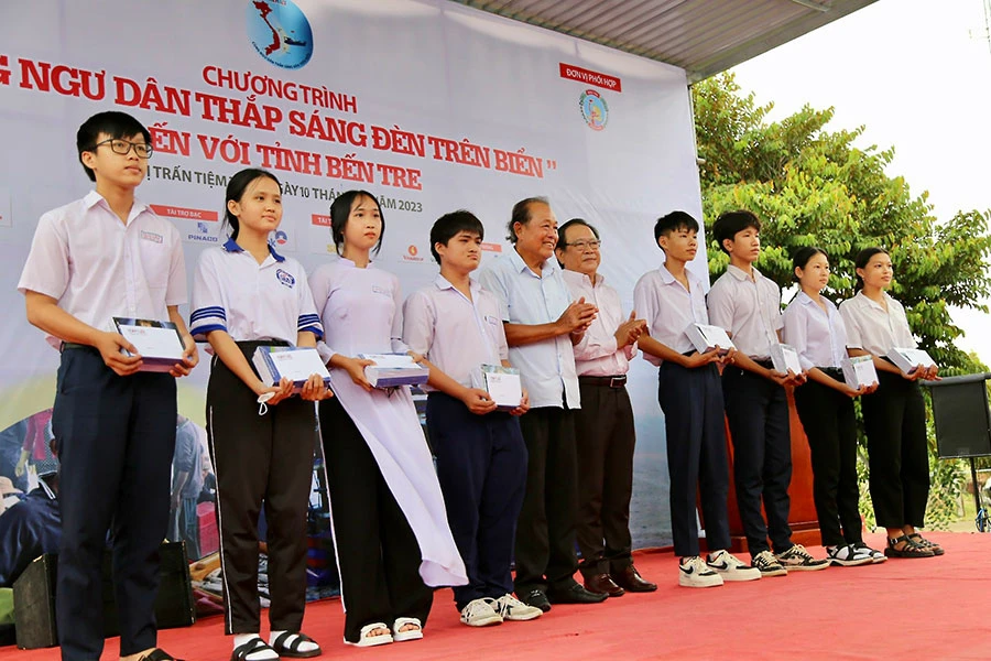 Ông Trương Hòa Bình, nguyên Phó Thủ tướng thường trực Chính phủ, Chủ tịch danh dự của chương trình, cùng ông Mai Ngọc Phước, Tổng Biên tập báo Pháp Luật TP.HCM, trao học bổng cho con em ngư dân tỉnh Bến Tre. Ảnh: HD P45_Hình1.jpg