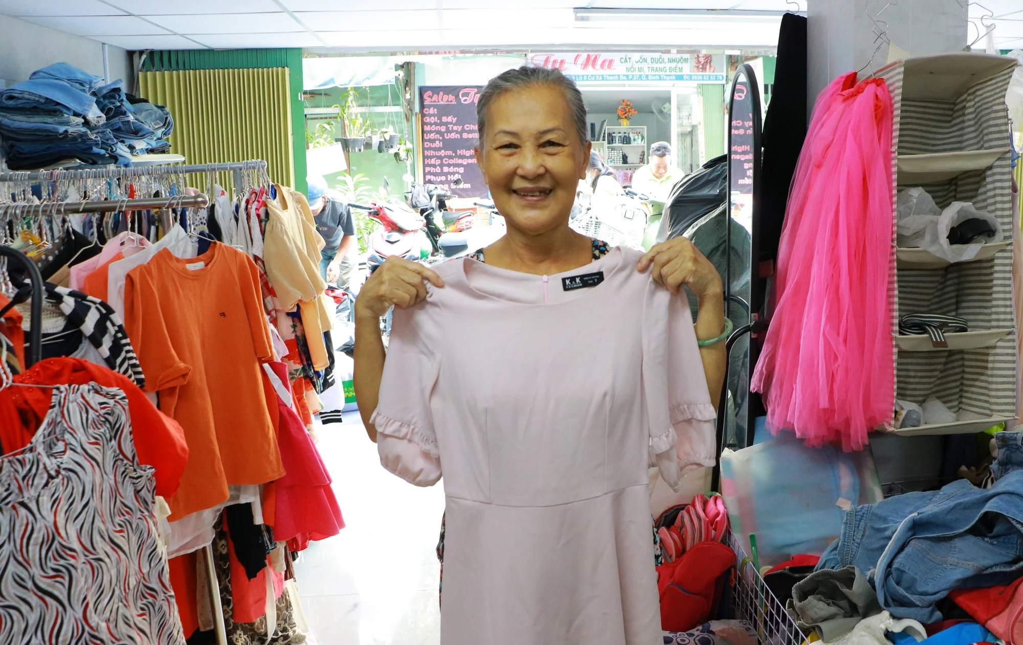 Bà Thập (ngụ Bình Thạnh) vui vẻ ướm thử chiếc váy vừa lựa được để Tết mặc. Có mặt từ sớm, bà Thập cũng lựa được cho con trai hai cái áo lao động để mặc đi làm. "Quần áo ở đây rất đẹp và mới, nhờ gian hàng 0 đồng mà tôi có thể tiết kiệm được một khoảng mua quần áo dịp Tết"- bà Thập cười nói. quan-ao-0-dong-4-7418.jpg