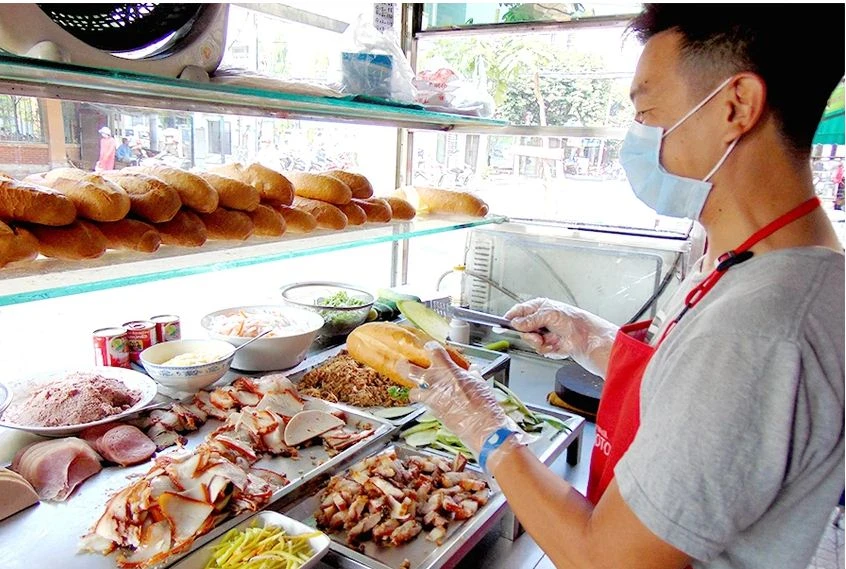 Một quầy bán bánh mì tuân thủ các hướng dẫn an toàn vệ sinh thực phẩm theo hướng dẫn từ cơ quan chức năng. Ảnh: T.N che bien thuc pham an toan 1-tran ngoc.JPG