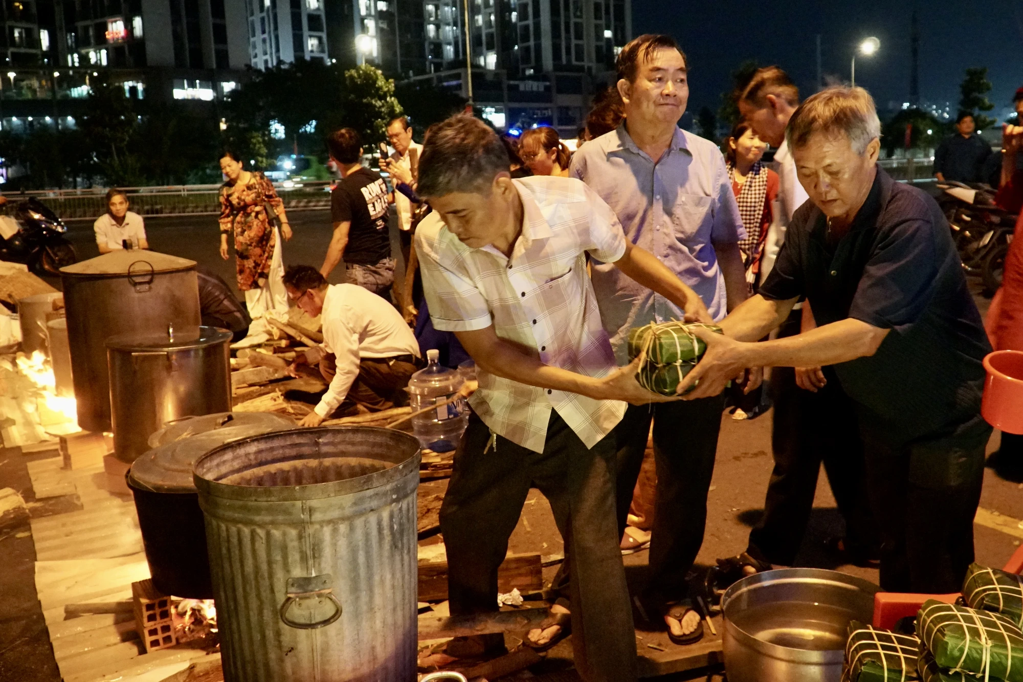 Ông Nguyễn Trung Hậu, ngụ phường Tân Thuận Tây, (áo nâu kẻ caro) chuẩn bị nấu bánh trong ngày hội “Xuân đoàn kết - Tết nghĩa tình”. Ảnh: BẢO PHƯƠNG tet-nghia-tinh-17.JPG